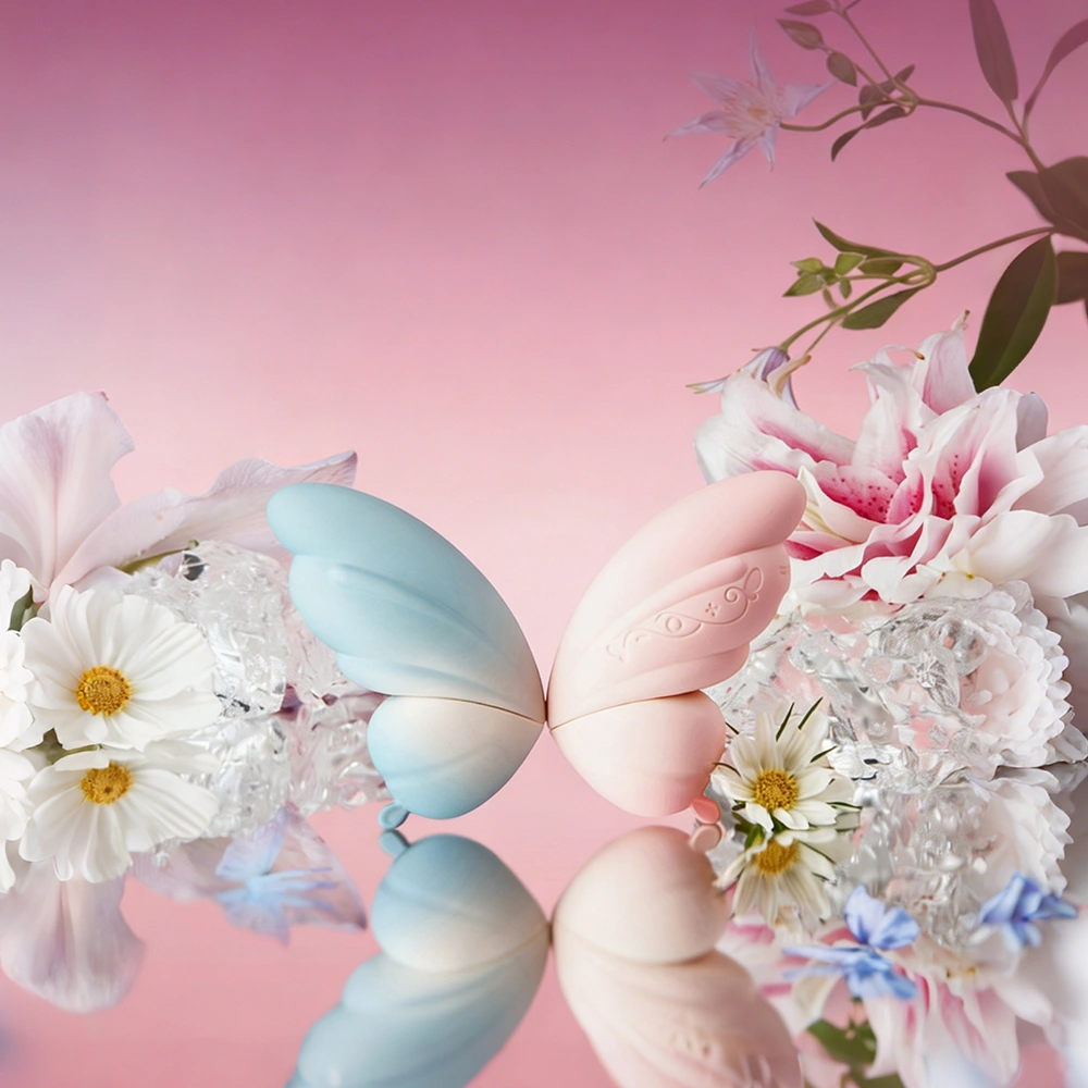 TAOF Liberty Blush and Celeste butterfly-shaped massagers reflecting on a crystal surface with delicate spring flowers.